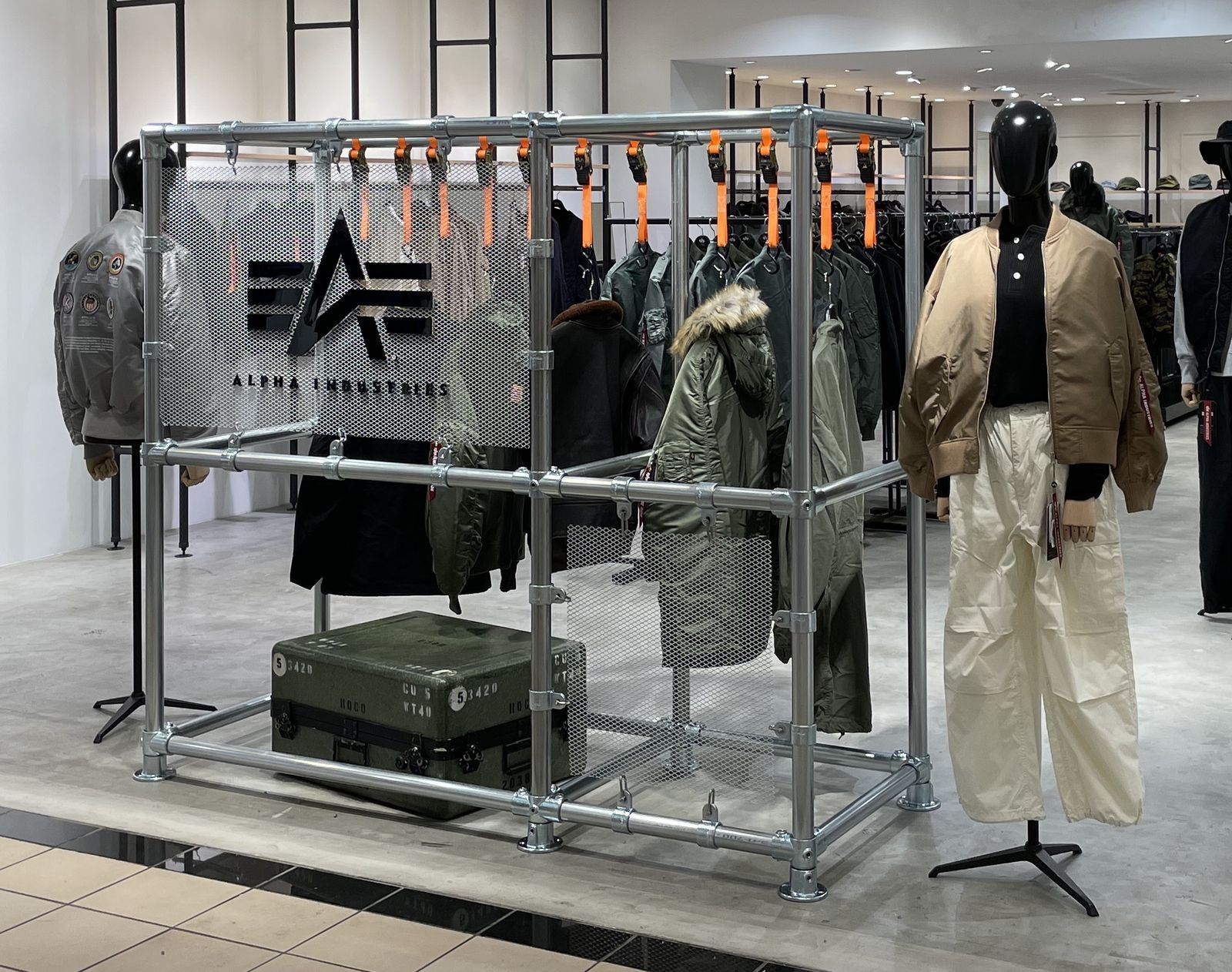 Pop-up store with a scaffold-pipe frame, mesh panel and orange belt displays