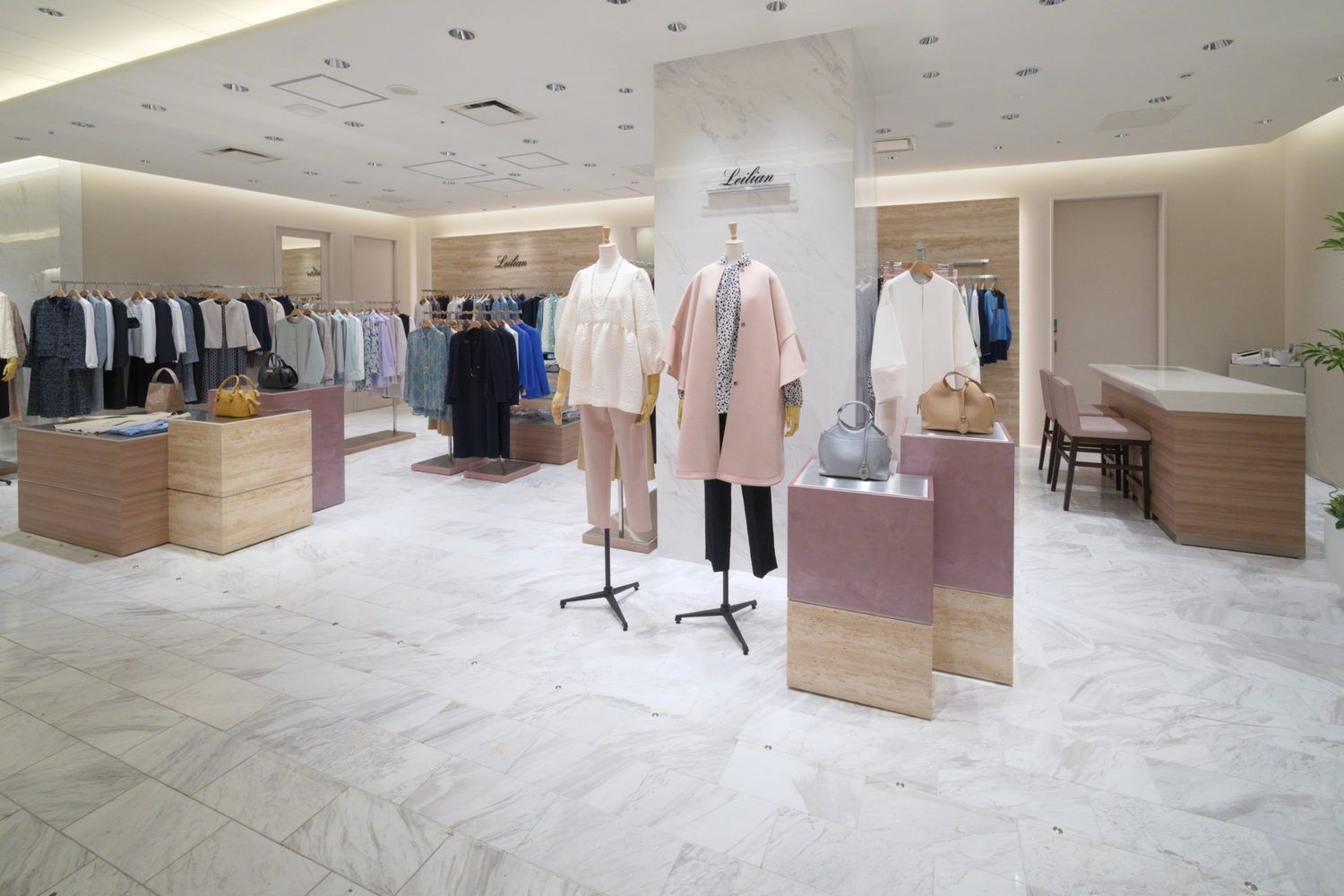 Womenswear boutique with pale stone, warm wood fixtures and soft pink accents